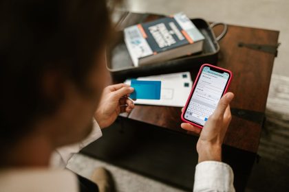 Pessoa realiza um pagamento online usando um smartphone e um cartão de crédito em ambiente interno.