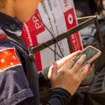 Agente policial uniformizada usa um smartphone ao ar livre em Londrina, no Paraná.